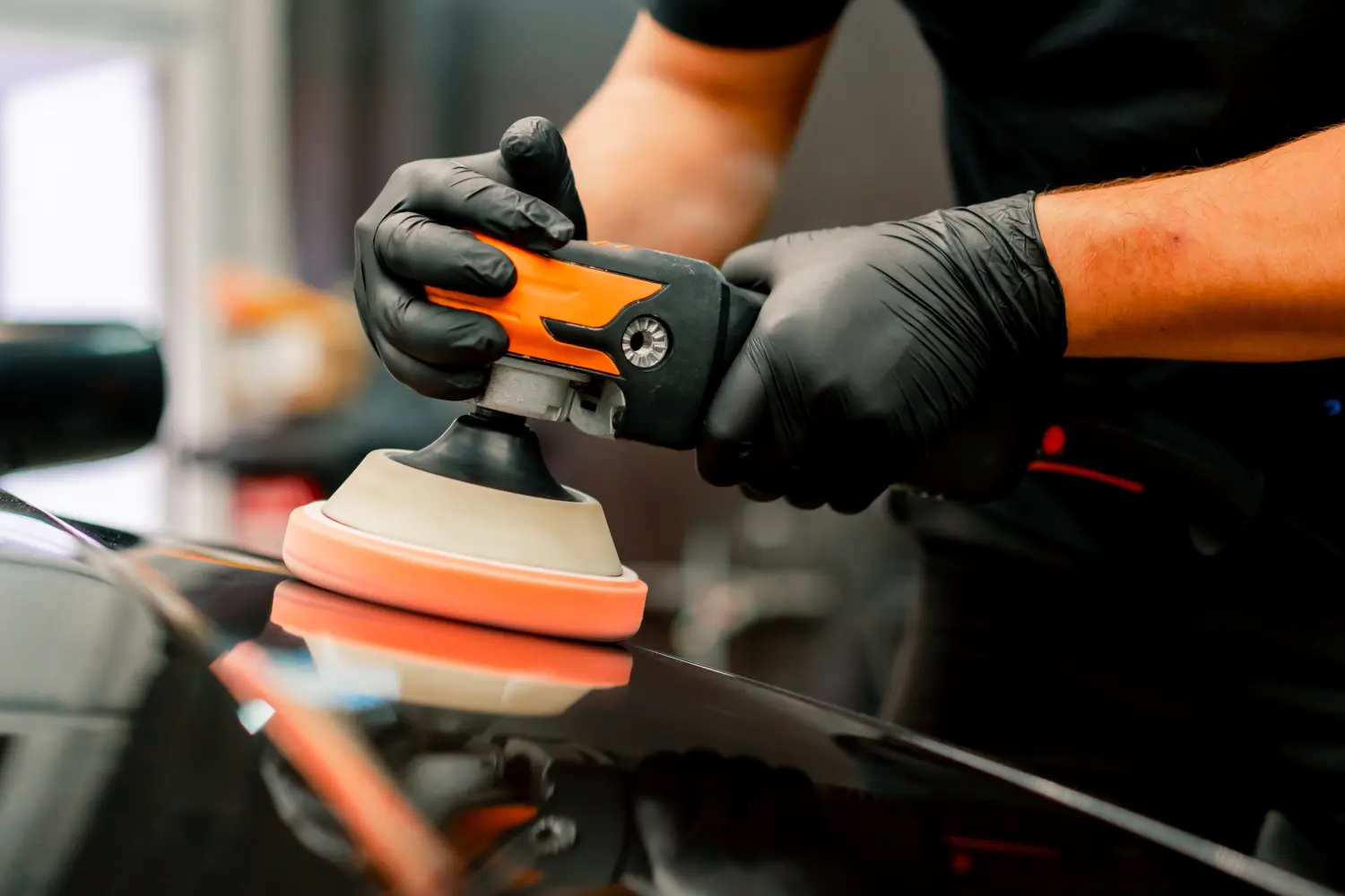,FB Consulting ,Nattheim , Ferhat Baygin , Audits, Wertstromanalysen ,  Projektmanagement , LieferantenentwickluàNahaufnahme eines Mitarbeiters einer Autowaschanlage, der mit einer Poliermaschine die Motorhaube eines schwarzen Luxuswagens poliert
